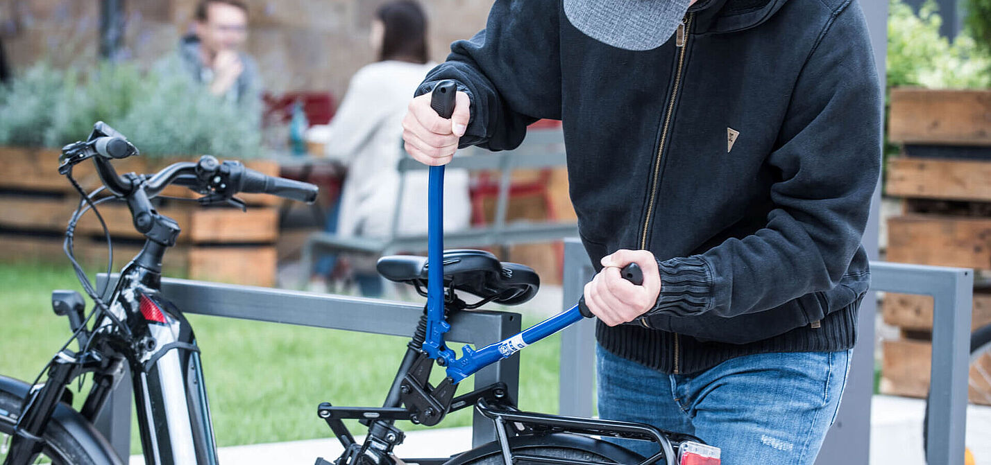 Fahrraddiebstahl mit einem Bolzenschneider Eine Person versucht, mit einem Bolzenschneider das Schloss eines Fahrrads zu knacken.